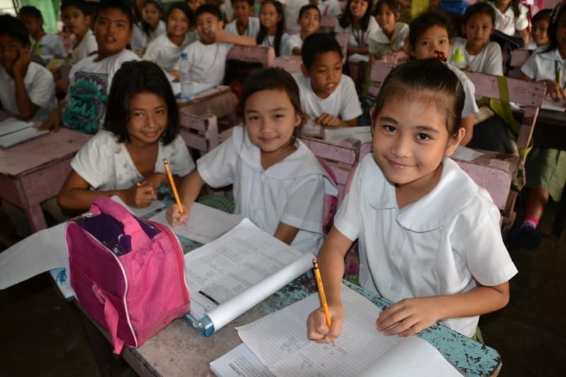 Skolejenter ved pultene sine i en lokal skole i Cavite.